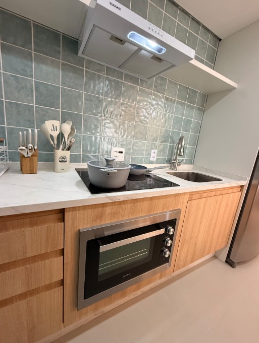 Cozinha — azulejos verde-acinzentados, marcenaria clara e bancada em mármore