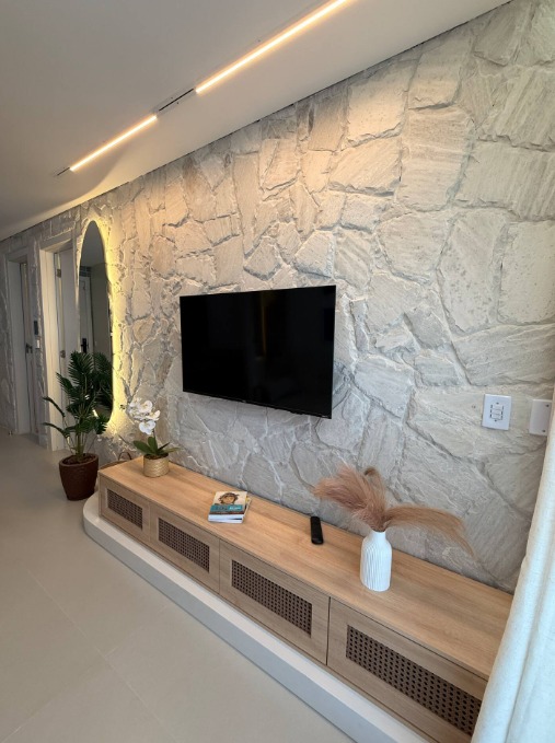 Sala de estar — painel em pedra natural, rack em madeira e iluminação linear