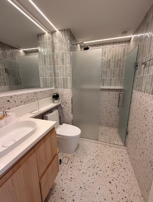Banheiro — revestimento cinza, granilite no piso e box em vidro fumê